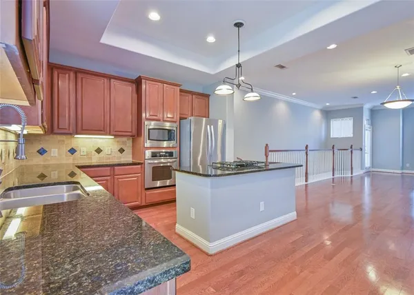 a large kitchen with stainless steel appliances a large counter top a stove and a sink
