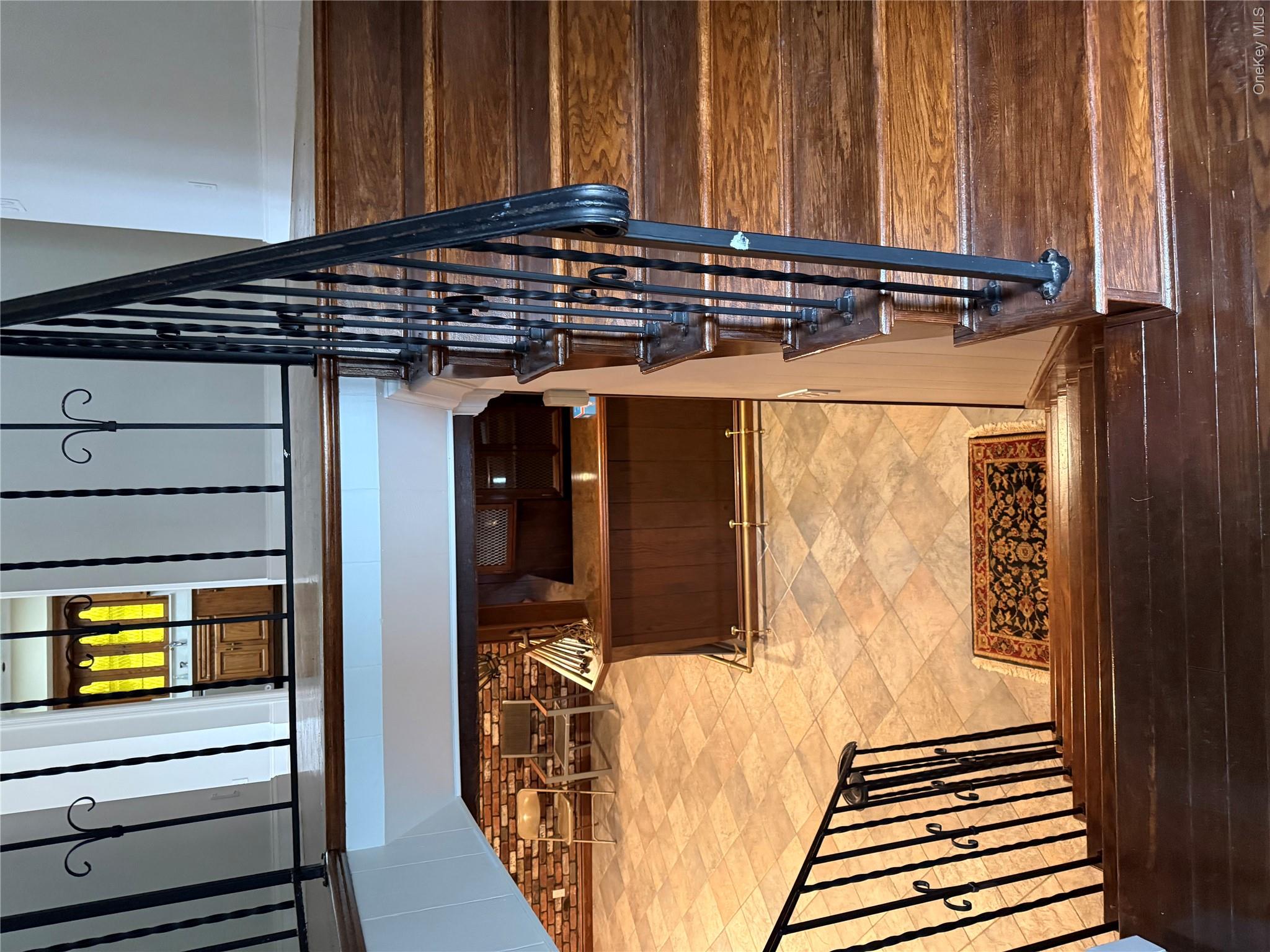 30 Dogwood Road Albertson, NY 11507 - Photo 12 of 20 The property features hardwood stairs with ornate wrought iron railings, leading down to a tiled floor area