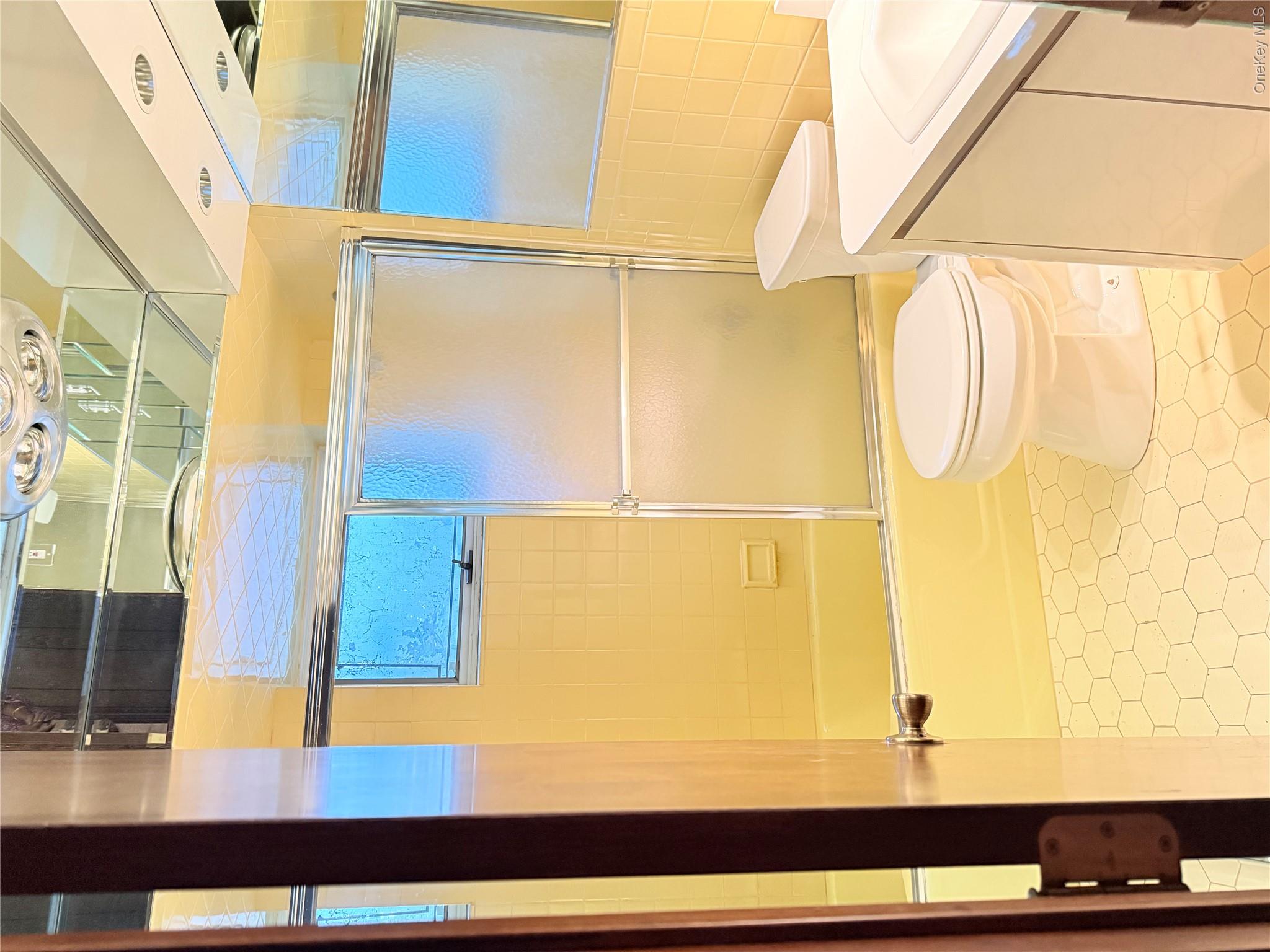 30 Dogwood Road Albertson, NY 11507 - Photo 14 of 20 Bathroom featuring hexagonal floor tiles, a bathtub with a sliding glass door, and a white vanity with an integrated sink