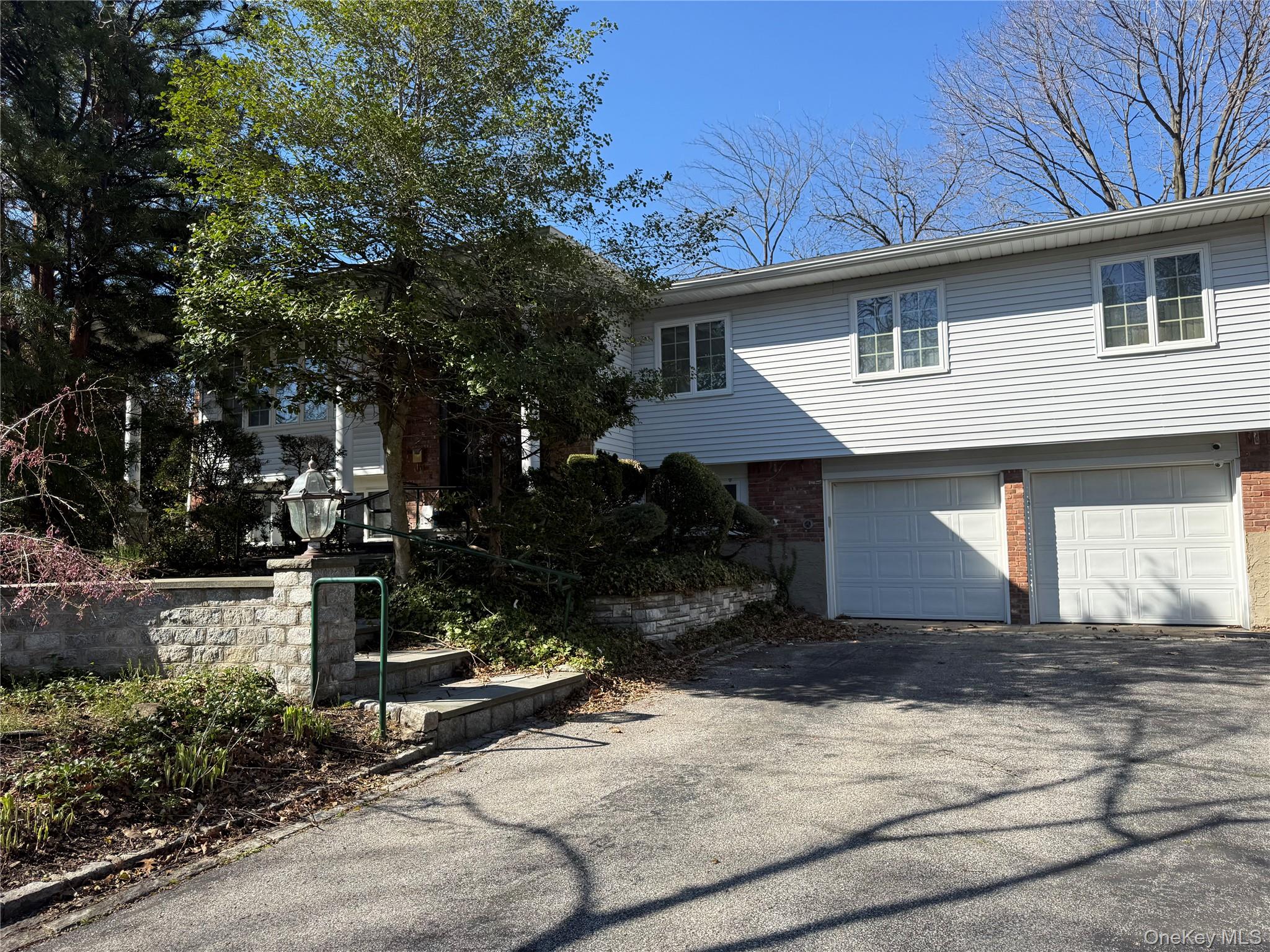 30 Dogwood Road Albertson, NY 11507 - Photo 2 of 20 The property features white siding, a brick facade, and two garage doors
