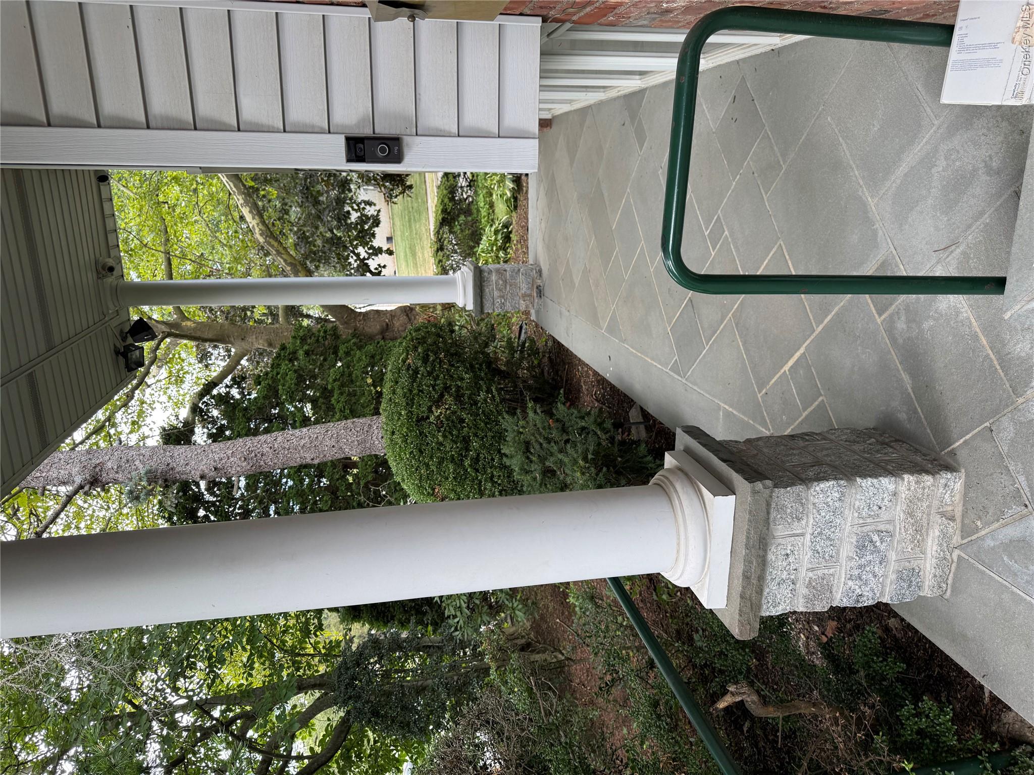 30 Dogwood Road Albertson, NY 11507 - Photo 5 of 20 The property features a stone paver walkway and a columned porch, with a view of mature trees and landscaping