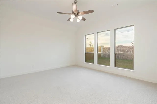 an empty room with a fan & a window