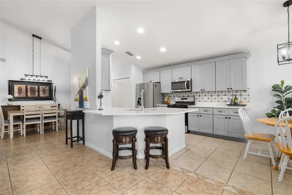 a kitchen with stainless steel appliances white cabinets a sink a stove a refrigerator a washer and dryer