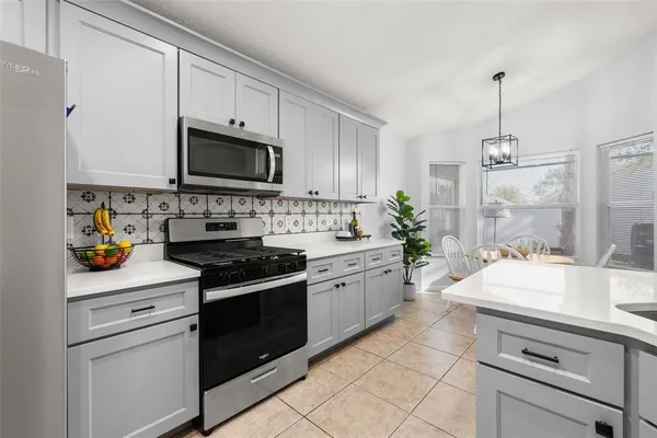 a large white kitchen with stainless steel appliances lots of counter space sink and a window