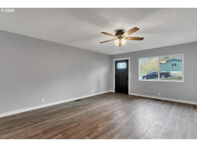 a view of an empty room with window and wooden floor