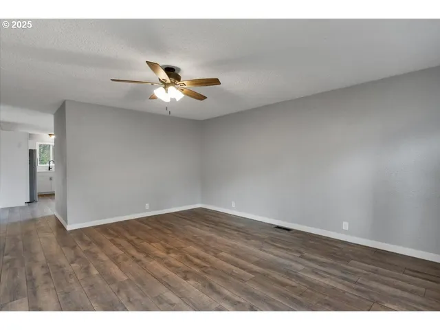 a view of an empty room with a ceiling fan and window