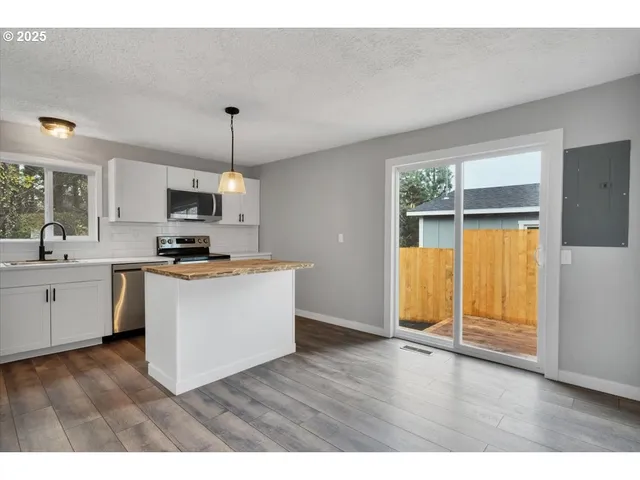 a kitchen with kitchen island granite countertop wooden floors stainless steel appliances and sink