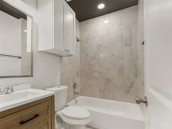 a bathroom with a granite countertop sink a toilet and shower
