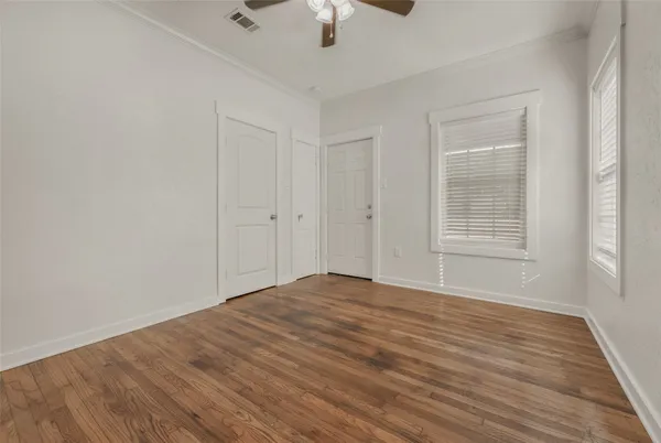 a view of an empty room with wooden floor closet and a window