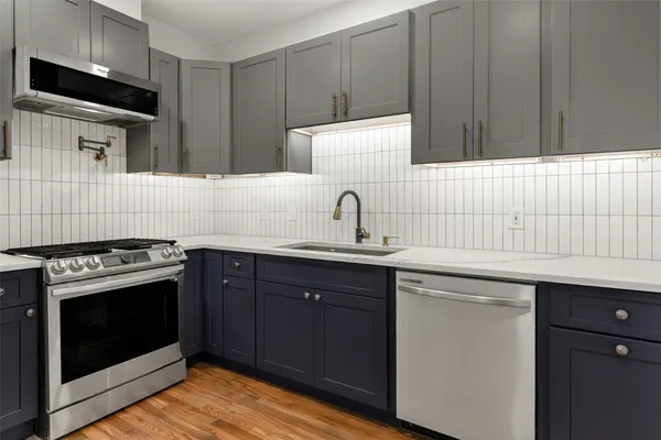 a kitchen with granite countertop a sink stainless steel appliances and cabinets