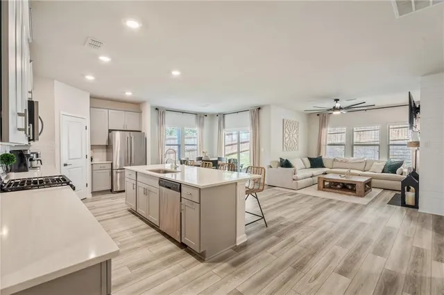 a kitchen with stainless steel appliances a sink a stove a refrigerator cabinets and a counter top space