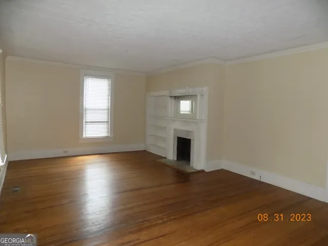 a view of empty room with wooden floor and fireplace