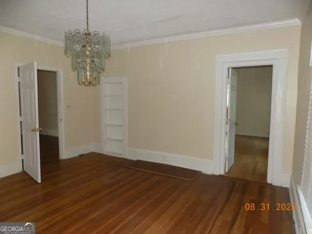 an empty room with wooden floor and hallway