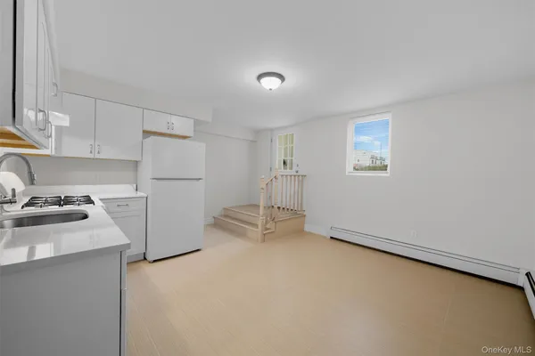 a kitchen with a refrigerator a stove top oven a cabinetry and a potted plant