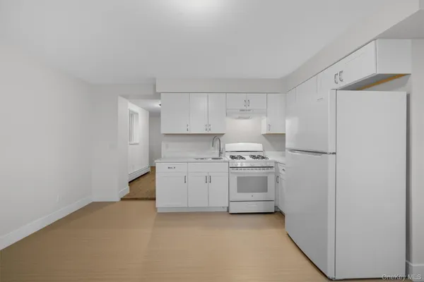 a kitchen with a stove a refrigerator and white cabinets