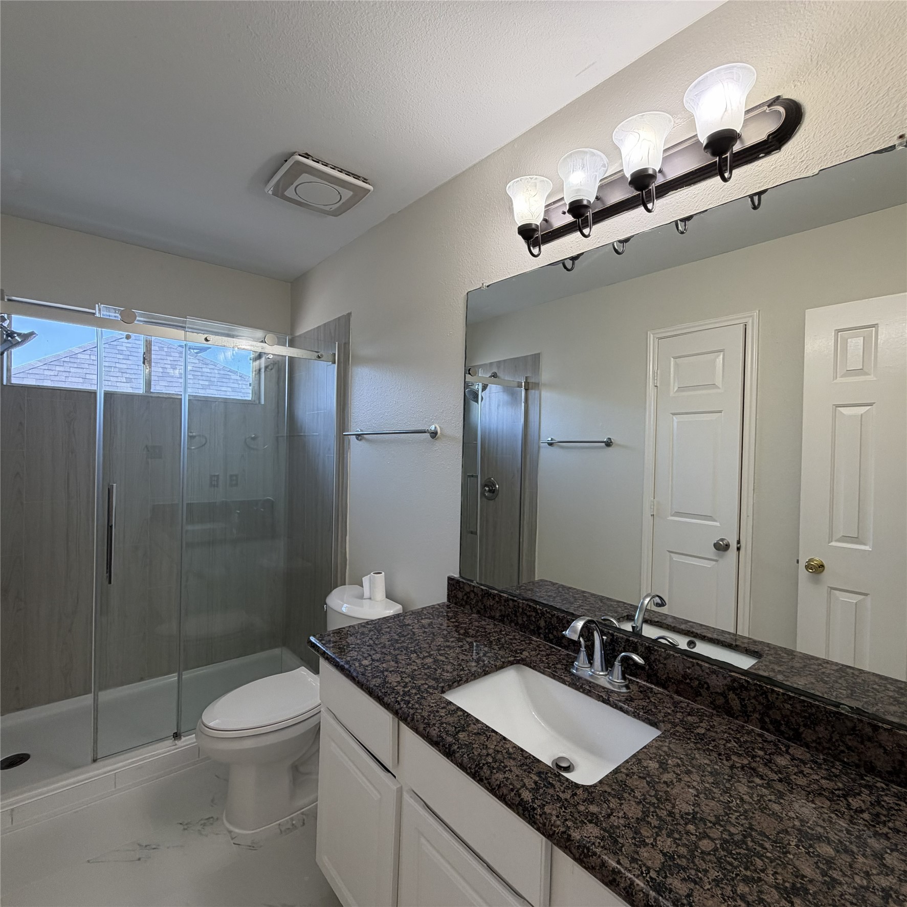 12219 Winderwick Lane Houston, TX 77066 - Photo 34 of 36 a bathroom with a granite countertop sink a toilet a mirror and shower