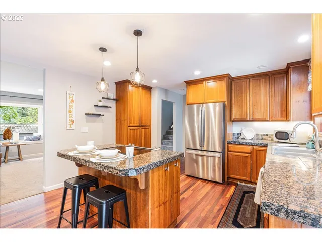 a kitchen with stainless steel appliances granite countertop a stove refrigerator and a view of living room