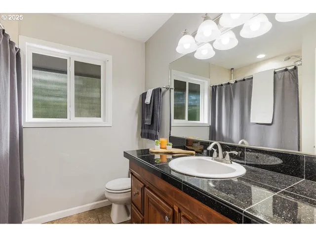 a bathroom with a granite countertop sink a toilet and a mirror