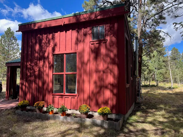 a view of wooden house with a large window and wooden fence