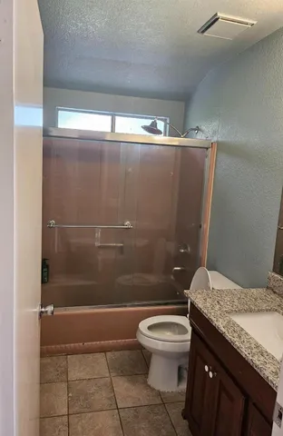 a bathroom with a granite countertop sink a toilet and shower