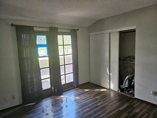 an empty room with wooden floor and windows
