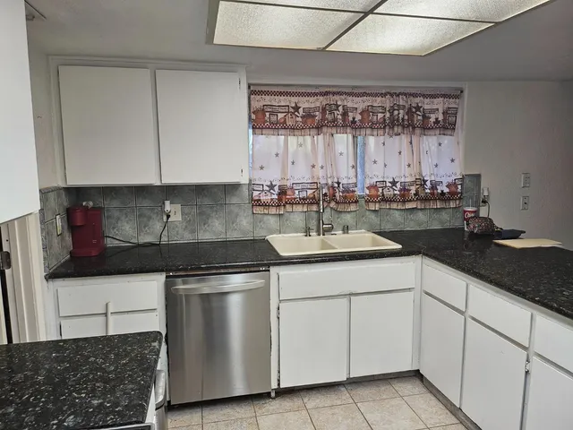 a kitchen with white cabinets and sink