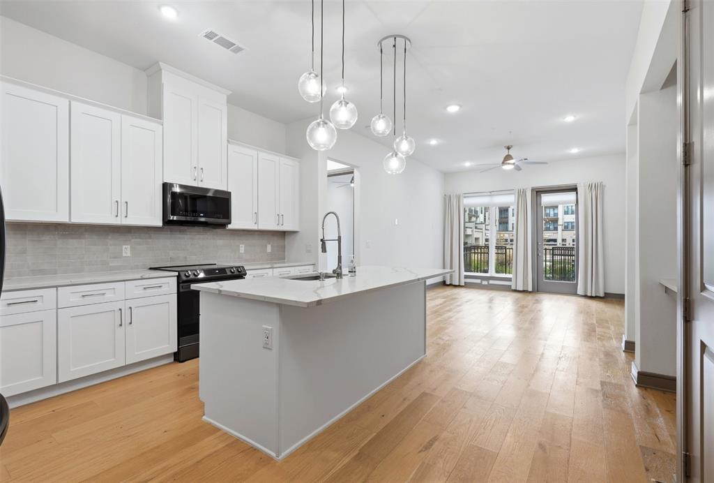 a large kitchen with granite countertop a large center island a sink stainless steel appliances and cabinets