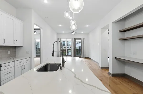 a large white kitchen with stainless steel appliances granite countertop a stove a sink dishwasher and white cabinets with wooden floor