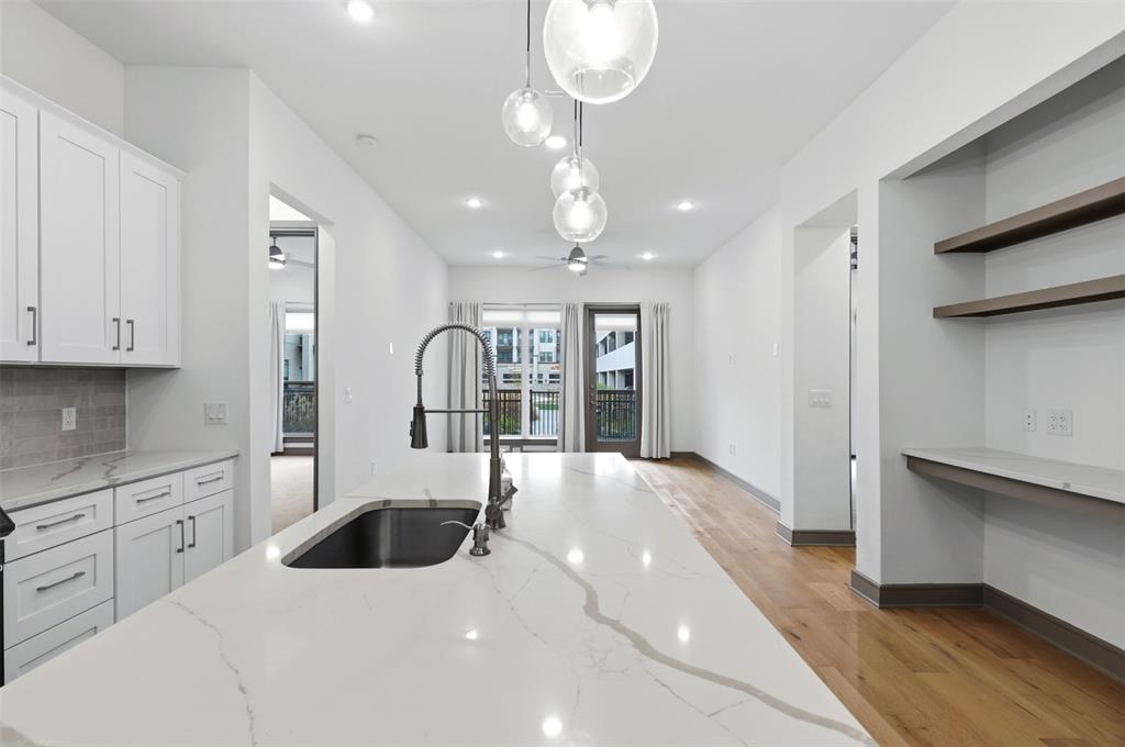 2700 Old Denton Road, Unit 1044 Carrollton, TX 75007 - Photo 5 of 39 a large white kitchen with stainless steel appliances granite countertop a stove a sink dishwasher and white cabinets with wooden floor