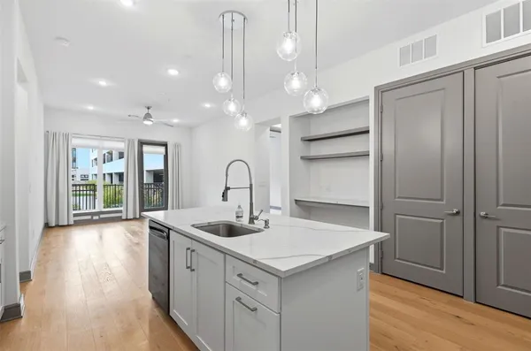a kitchen with a sink chandelier and wooden floor