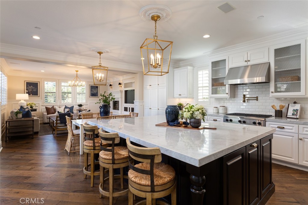 a kitchen with stainless steel appliances kitchen island granite countertop a dining table chairs stove and white cabinets
