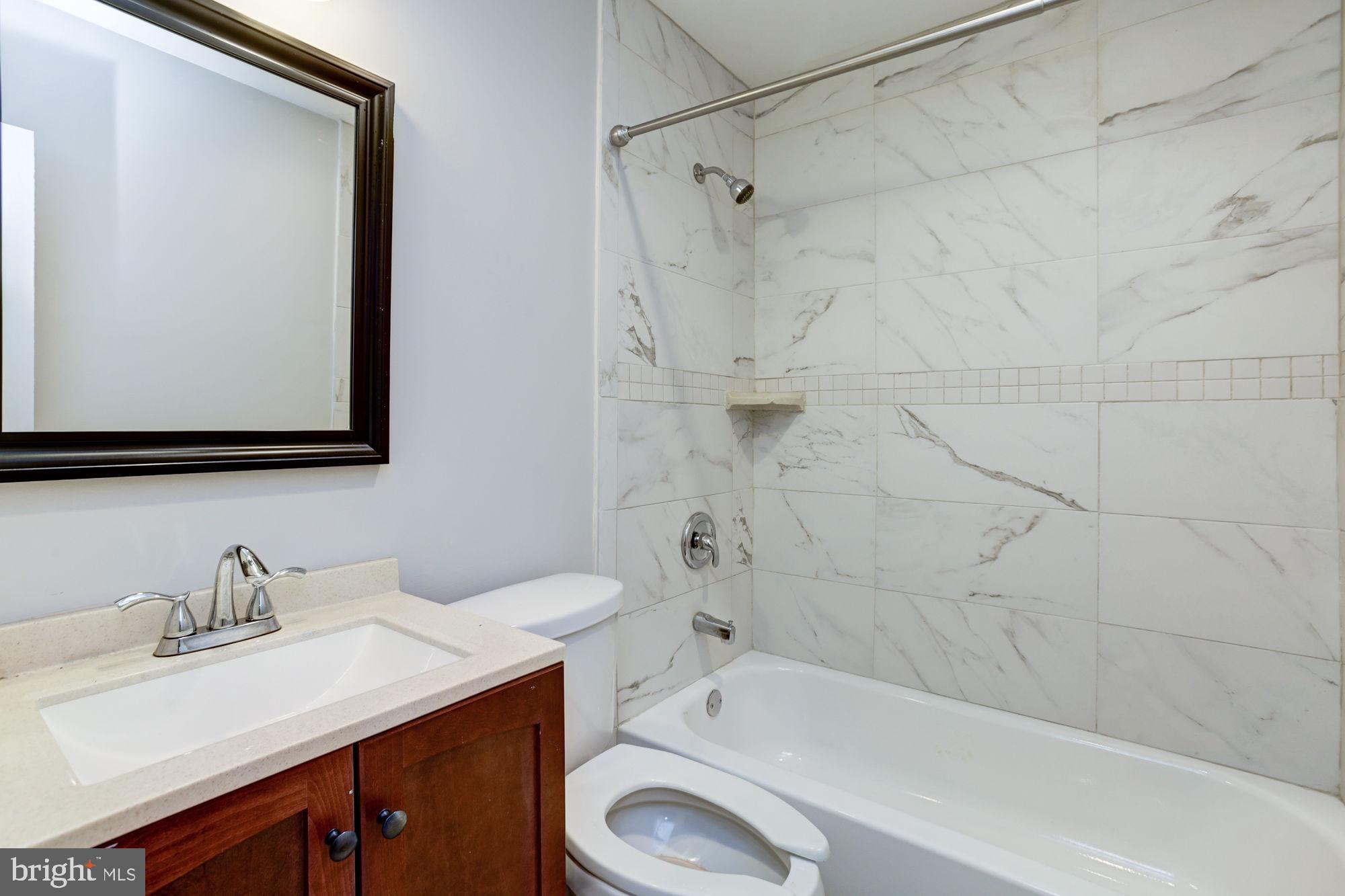 3315 Eastern Avenue, Unit 203 Baltimore, MD 21224 - Photo 13 of 13 a bathroom with a granite countertop sink toilet and shower
