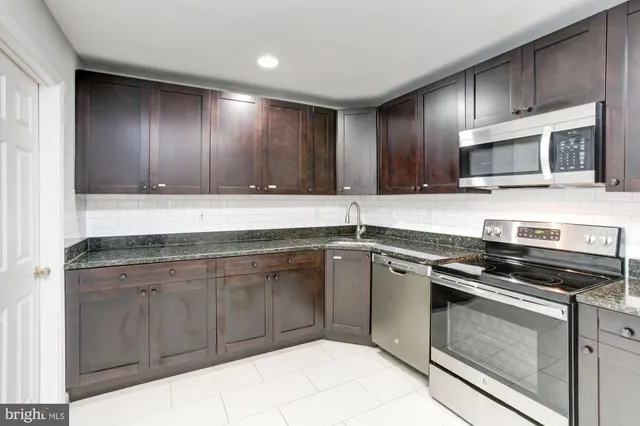 a kitchen with stainless steel appliances granite countertop wooden cabinets and a stove top oven