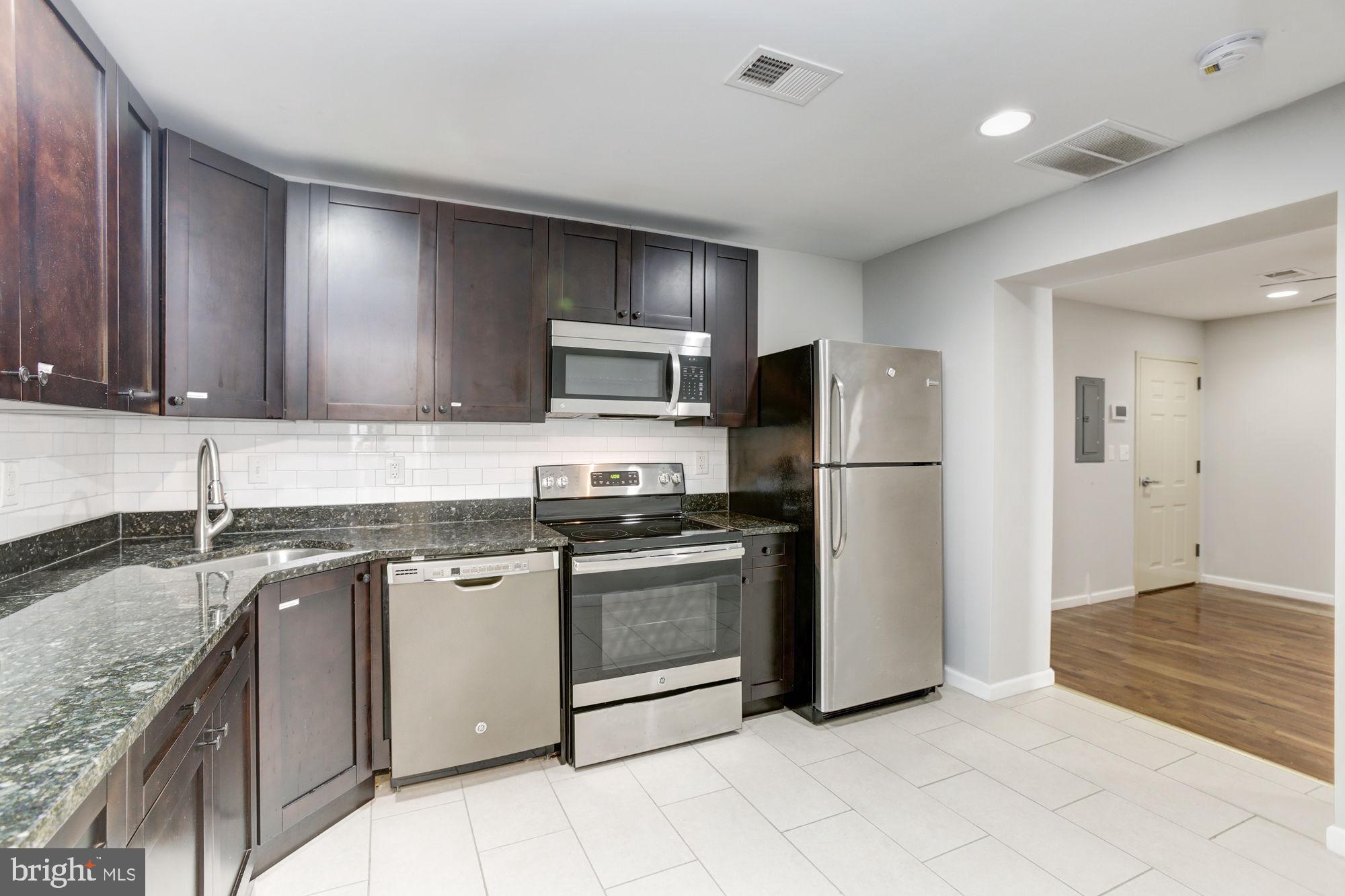 3315 Eastern Avenue, Unit 203 Baltimore, MD 21224 - Photo 6 of 13 a kitchen with stainless steel appliances granite countertop a refrigerator a stove a sink and a microwave