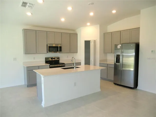 a kitchen with stainless steel appliances refrigerator a microwave and white cabinets