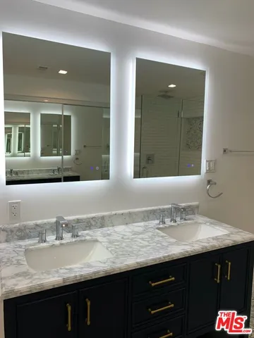 a bathroom with a granite countertop sink two mirror and a