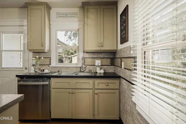 a kitchen with stainless steel appliances granite countertop a sink and a stove next to a window