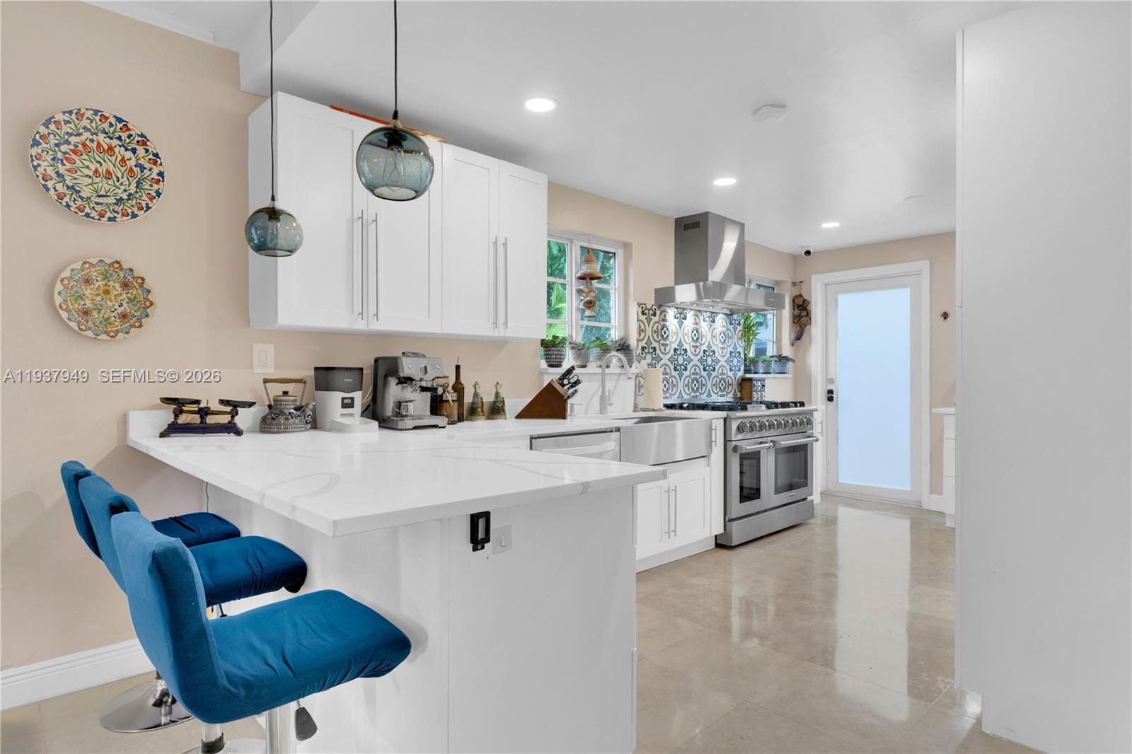 4739 Southwest 5th Street Miami, FL 33134 - Photo 3 of 40 a kitchen with stainless steel appliances kitchen island granite countertop a sink a stove a refrigerator and a dining table with wooden floor