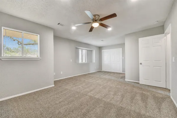 an empty room with windows and fan