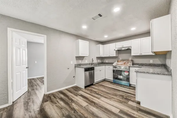 a kitchen with granite countertop white cabinets and white appliances