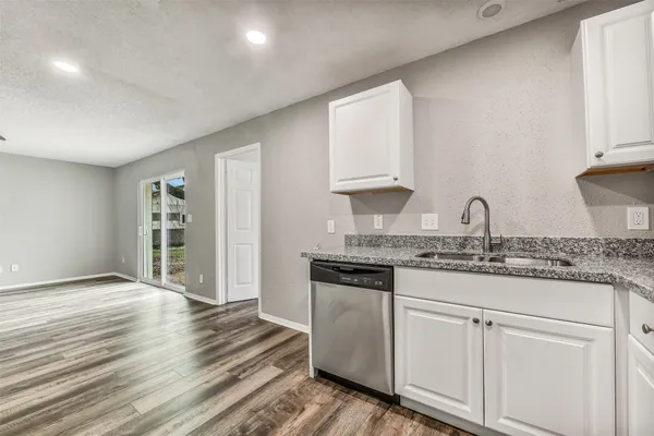 a kitchen with granite countertop a sink cabinets and wooden floor