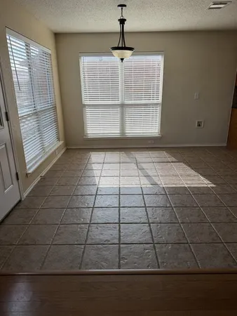 an empty room with wooden floor fireplace and windows