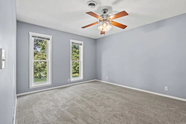 an empty room with windows and a ceiling fan