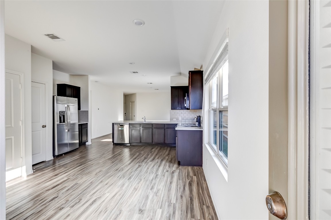 545 Greatest Gift Way Jarrell, TX 76537 - Photo 17 of 34 Kitchen with light countertops, a peninsula, stainless steel appliances, light wood-type flooring, and tasteful backsplash