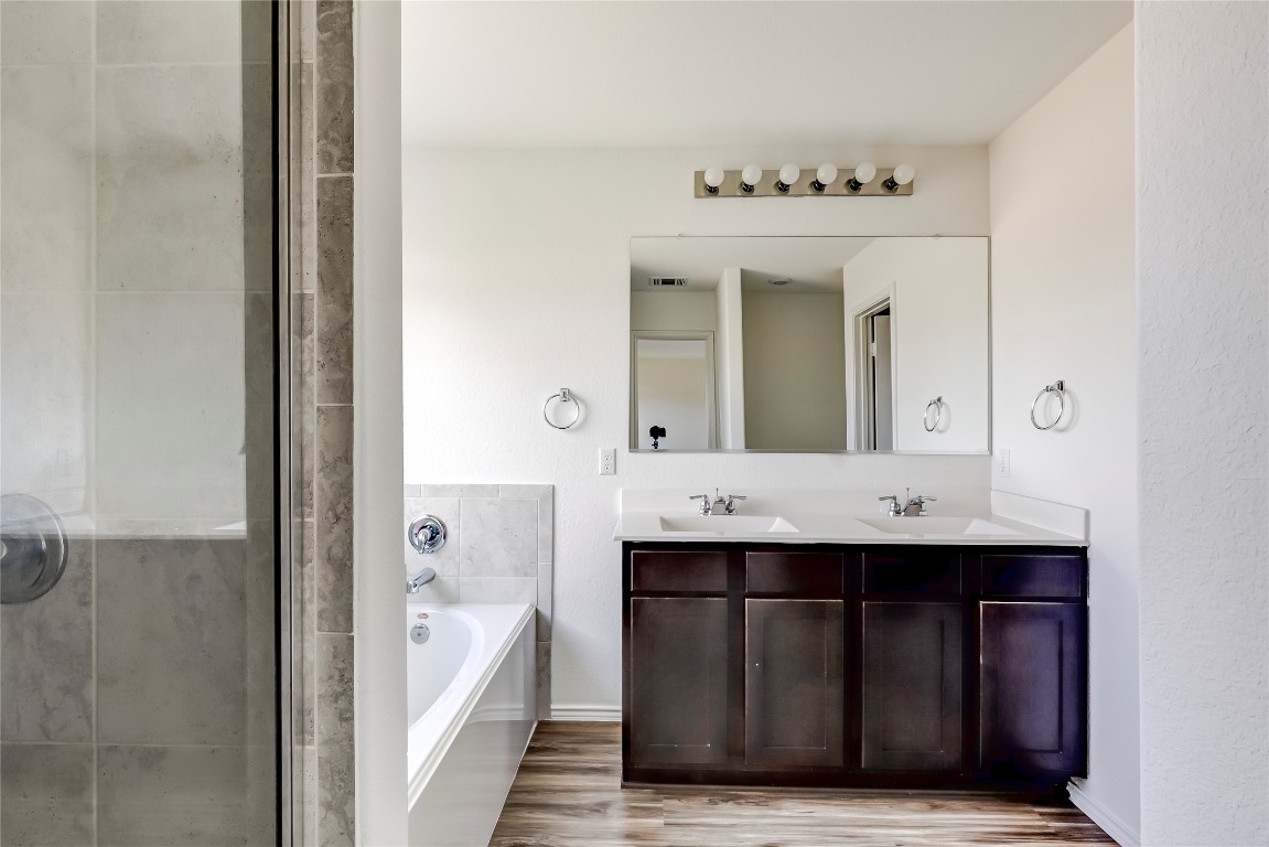 545 Greatest Gift Way Jarrell, TX 76537 - Photo 22 of 34 Full bath with a bath, double vanity, light wood-style floors, and a shower stall