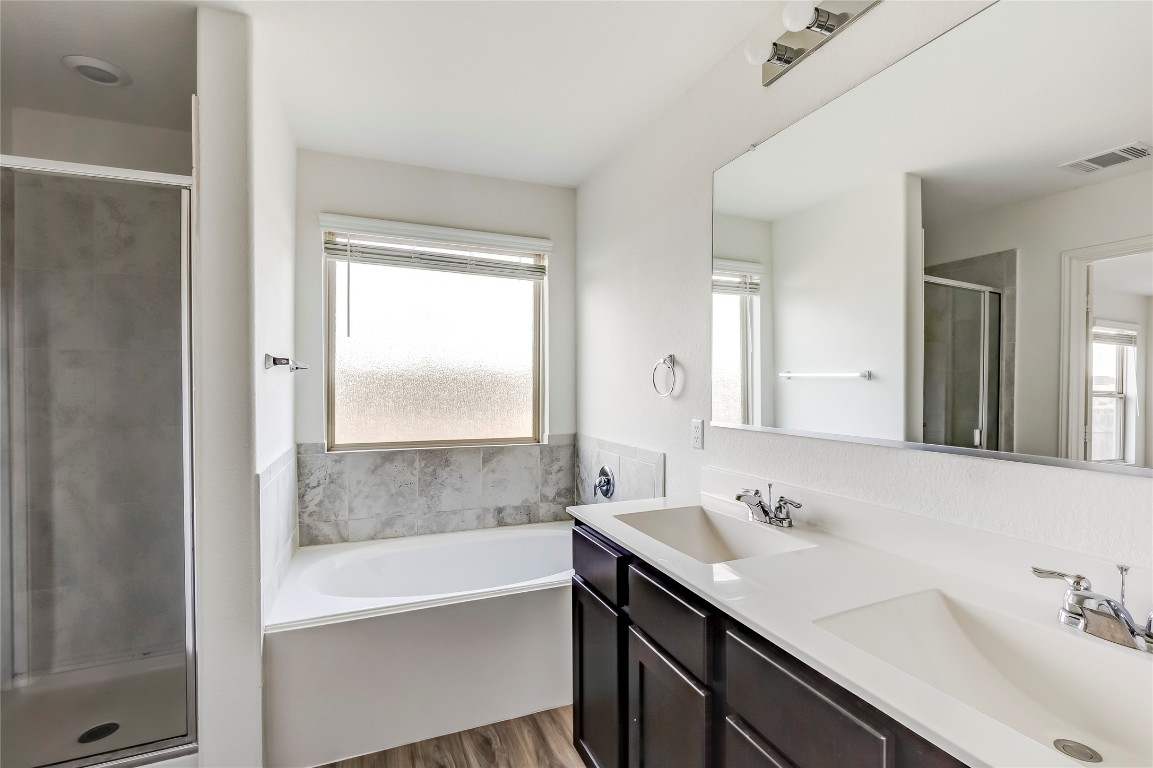 545 Greatest Gift Way Jarrell, TX 76537 - Photo 23 of 34 Full bathroom featuring a stall shower, double vanity, a garden tub, and dark wood-style flooring