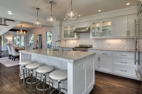 a kitchen with stainless steel appliances kitchen island granite countertop a table chairs in it and wooden floors