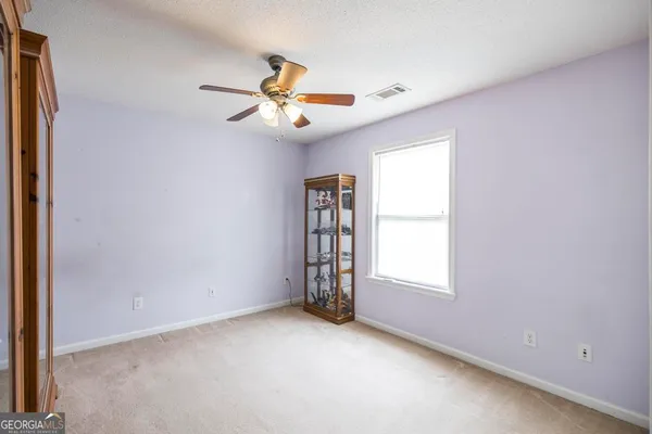 an empty room with windows and fan