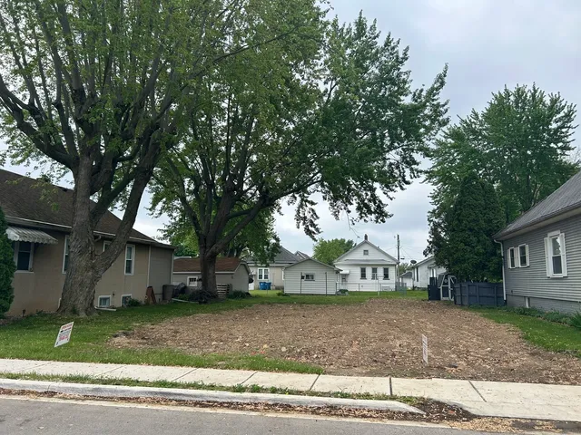 a view of a house with a yard and large trees