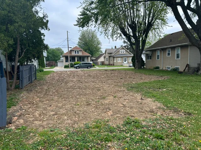 a front view of a house with a garden and trees
